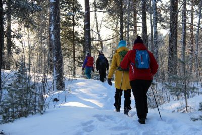 Ihmisiäkävelemässä lumisella metsäpolulla